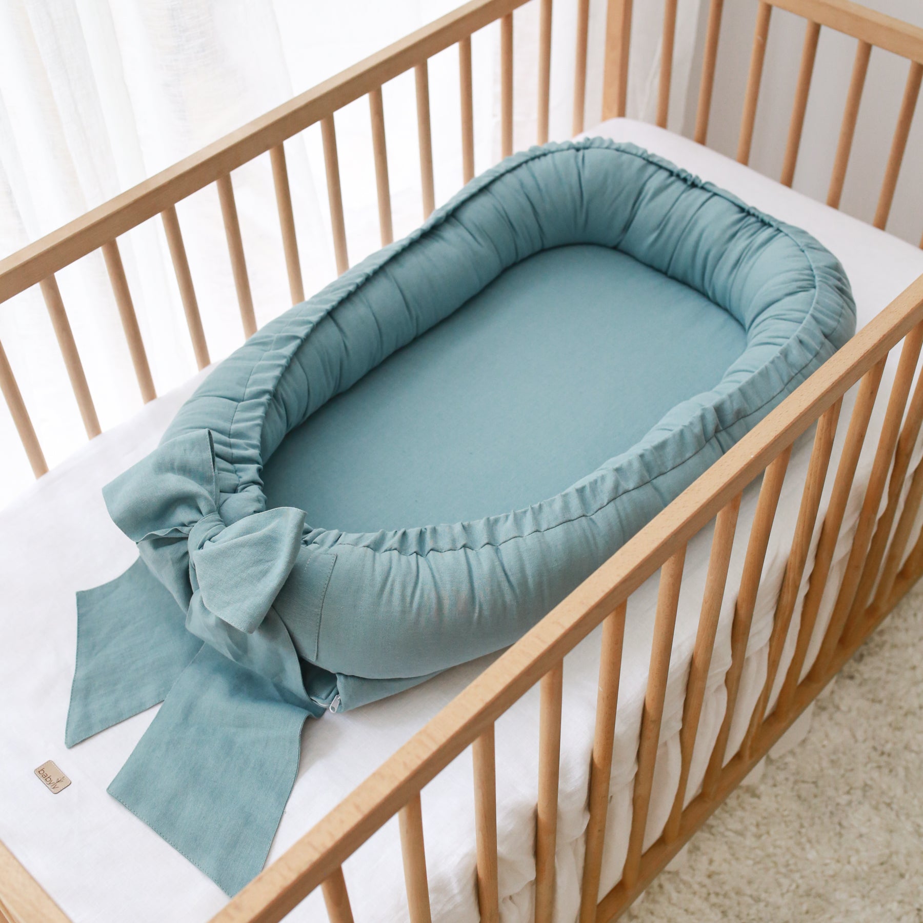 Linnen babynest met strik – Comfortabel en veilig voor pasgeborenen.
