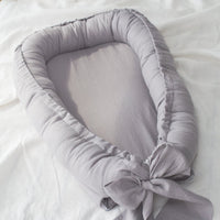 Linnen babynest met strik – Comfortabel en veilig voor pasgeborenen.