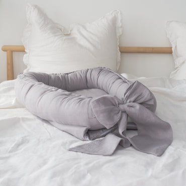 Linnen babynest met strik – Comfortabel en veilig voor pasgeborenen.